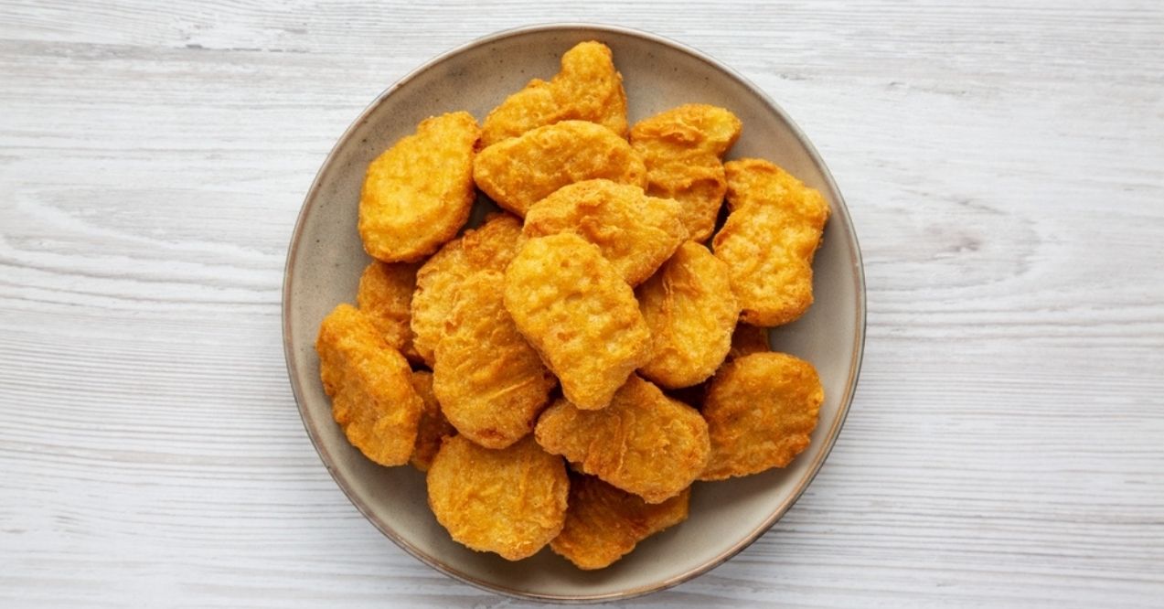 Plate of golden chicken nuggets on a light wood background