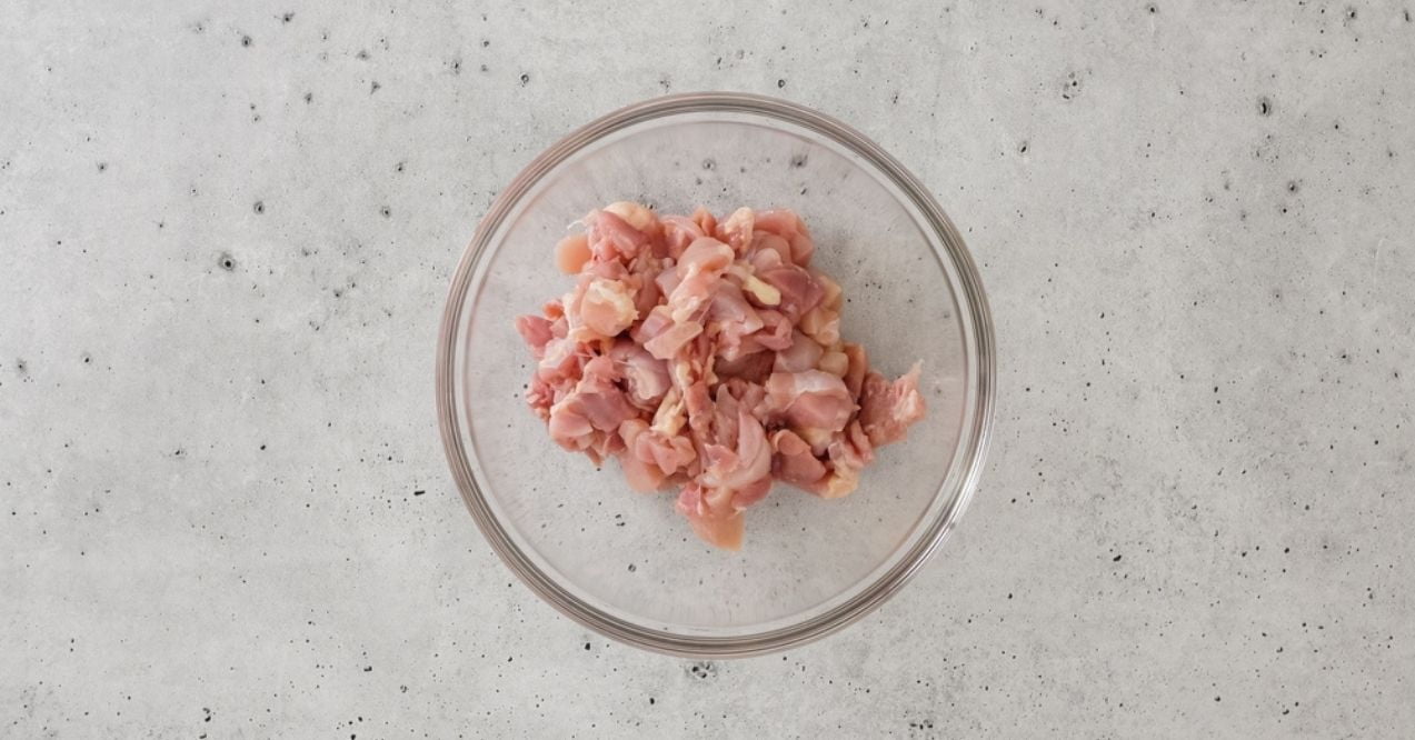 Bowl of raw chicken pieces on a concrete surface