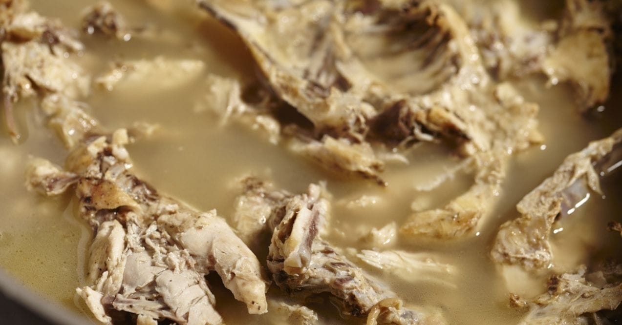 Close-up view of cooked chicken pieces in bone broth