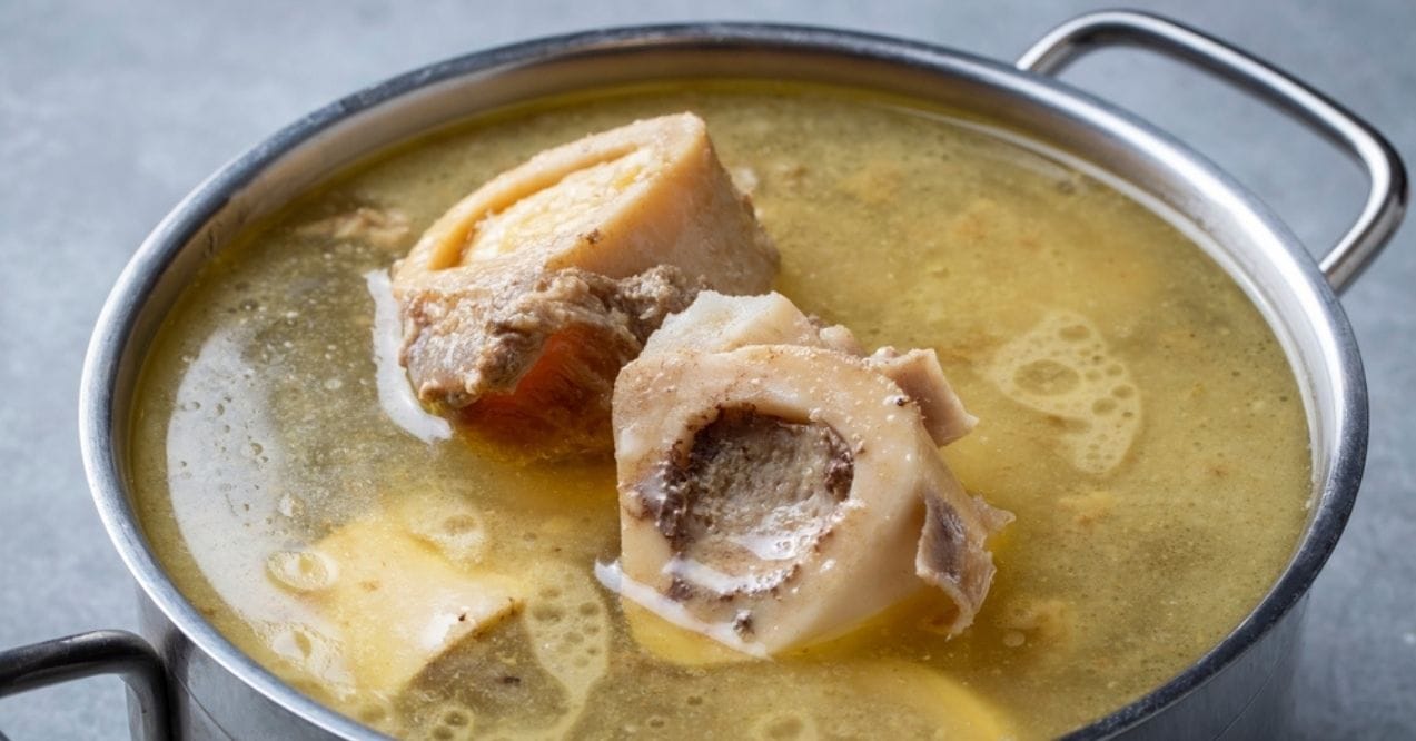 A pot of simmering bone broth with visible bones