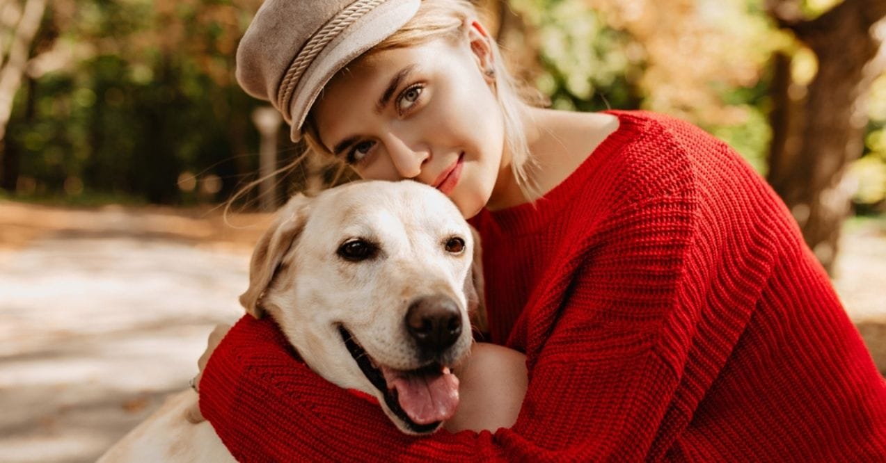 A girl hugging her Labrador Retriever in a park