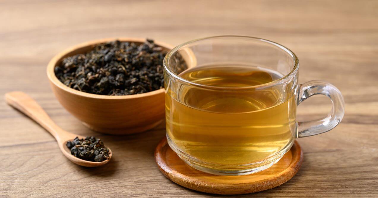 A cup of green tea with loose leaves, highlighting its potential for gut health and natural detox.